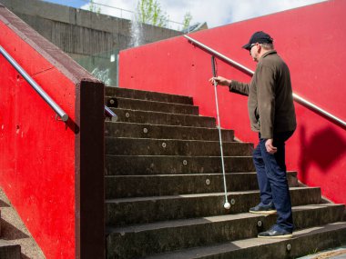 Kör bir adam parka çıkmak için rehber bastonunu kullanıyor.