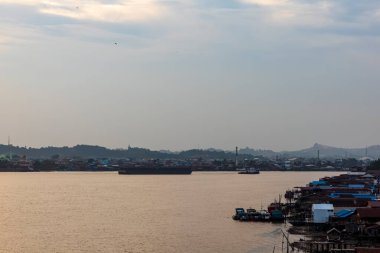 Güneş battığında Mahakam Nehri manzarası nehir etrafındaki gemi ve binalarla süslenir..