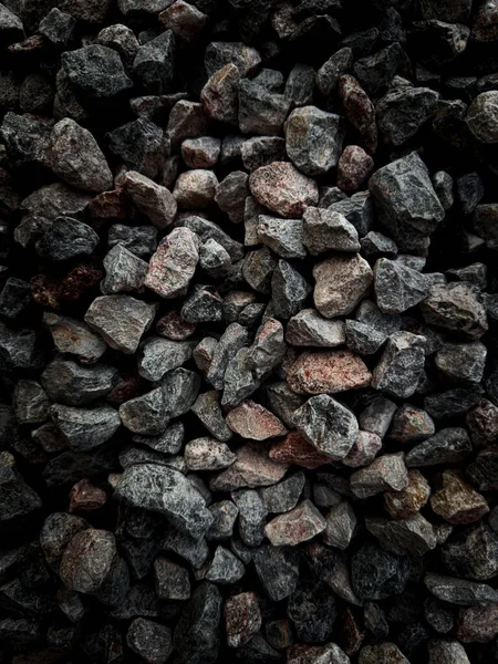 stock image Isolated close up many crushed stone ground floor background. Selective focus center granite gravel texture with dark colors