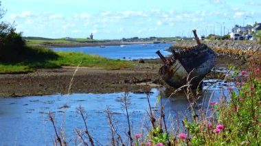 An old ship lies in the shallow water of the ocean at low tide Ireland
