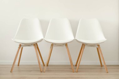 Ofiste ya da odada beyaz bir duvara karşı üç boş beyaz sandalye, boş yer. Yüksek kalite fotoğraf