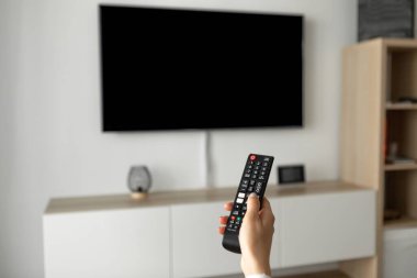 Bir adam televizyon izler ve uzaktan kumandayı kullanır. Yüksek kalite fotoğraf