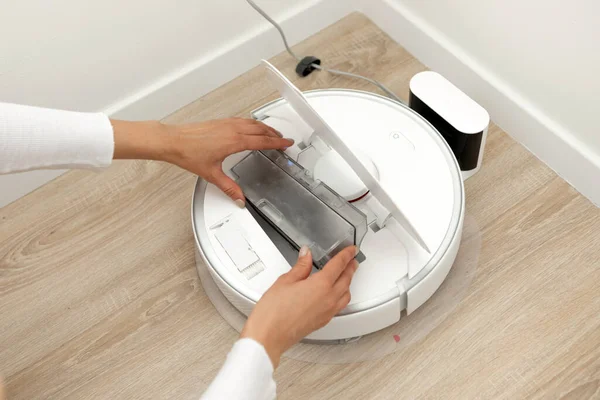 stock image Faceless young woman emptying the deposit of an automatic vacuum cleaner for cleaning the floor, a robot around the house. High quality photo