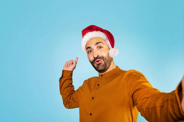 头戴圣诞礼帽的男人兴奋极了 站在蓝色背景下 手拿着手势 空空如也 高质量的照片 — 图库照片