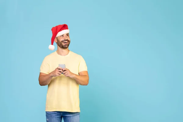 Kaukasischer Typ Mit Weihnachtsmütze Und Smartphone Blickt Den Kopierraum Blauer — Stockfoto