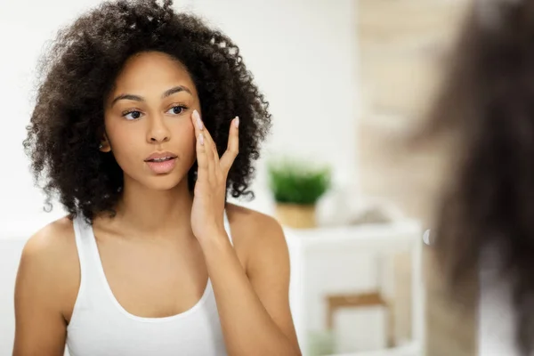 stock image Woman admiring her skin in front of a bathroom mirror, touching her face with her hand. High quality photo