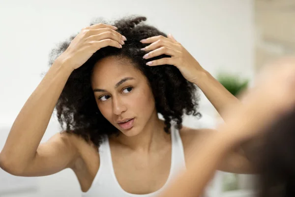 stock image Portrait of a beautiful young woman examining her scalp and hair in front of the mirror, hair roots, color, grey hair, hair loss or dry scalp problem. High quality photo