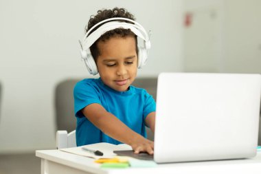 Odaklanmış Afro-Amerikalı adam dizüstü bilgisayarında mavi tişörtle ev içi oyunlar oynuyor. Yüksek kalite fotoğraf