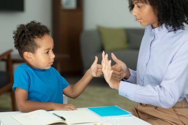 A smart boy counts on his fingers, studies with a private teacher in the office, a child learns numbers and how to count, sits at a table with a tutor. High quality photo