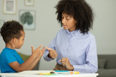 A smart boy counts on his fingers, studies with a private teacher in the office, a child learns numbers and how to count, sits at a table with a tutor. High quality photo
