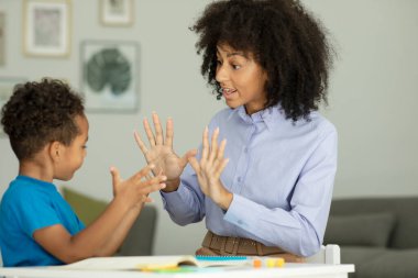 A smart boy counts on his fingers, studies with a private teacher in the office, a child learns numbers and how to count, sits at a table with a tutor. High quality photo