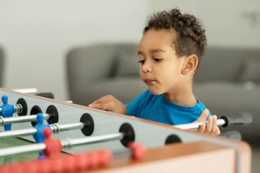 An African boy is having fun playing table football in a childrens play entertainment center. Hobby and leisure. High quality photo