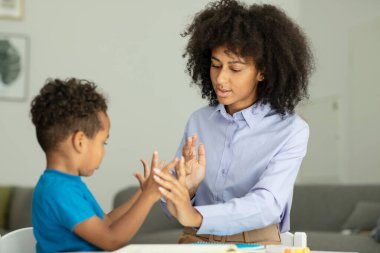 A smart boy counts on his fingers, studies with a private teacher in the office, a child learns numbers and how to count, sits at a table with a tutor. High quality photo