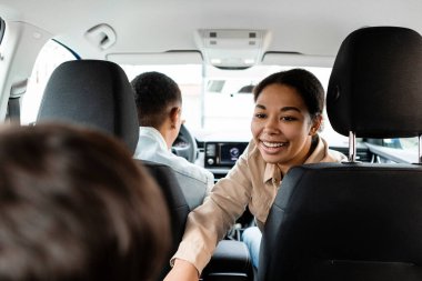 Mutlu siyah aile arabasının arkası, annesi çocuk, baba, anne ve çocuk tatilde yolculuk ederken konuşuyor.