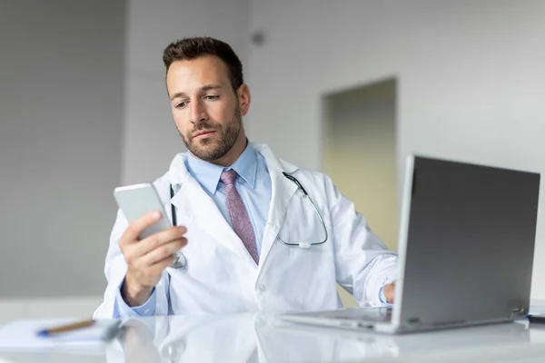 Medico Maschio Concentrato Uniforme Bianca Utilizzando Cellulare Consultando Pazienti Online — Foto Stock