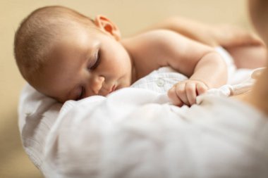 Annelik, annelik, çocuk bakımı. Anne, uyuyan bebeği elinde tutuyor, kızını sakinleştiriyor, yukarıdan bakıyor, yakın plan.