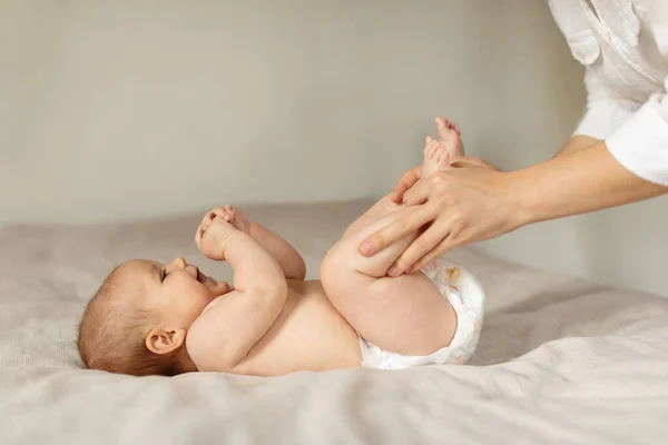 婴儿便秘 妈妈和新生的孩子一起做体操来释放气体 移动孩子的腿 婴儿躺在床上 复制空间 — 图库照片