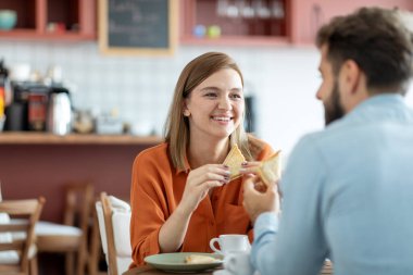 Kafkasyalı genç bir çift kahve içiyor ve kafeteryada veya kafede sandviç yiyor, içeride keyifli sohbetler yapıyorlar. İnsanlar, tarih, aşk ve yaşam tarzı konsepti