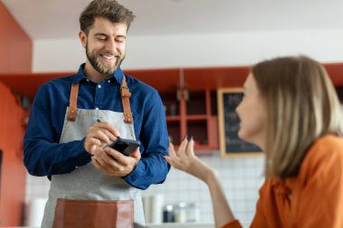 Garson, kadın müşteri siparişi vermek için akıllı telefon ya da dokunmatik ped kullanıyor. Kahve dükkanı için modern kablosuz teknoloji