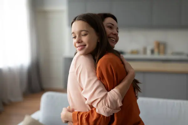 Mother-daughter bond. Loving mother hugging her teenage daughter, demonstrating unconditional love for child, spending time together at home