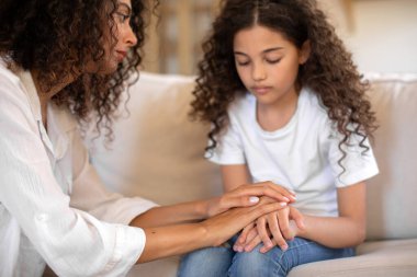 Kızının elini tutan şefkatli bir anne. Stresli bir kız. Zihinsel sorunları, depresyonu ya da sosyal sorunları var. Anne sakinleştirici çocuk, evde kanepede oturuyor.