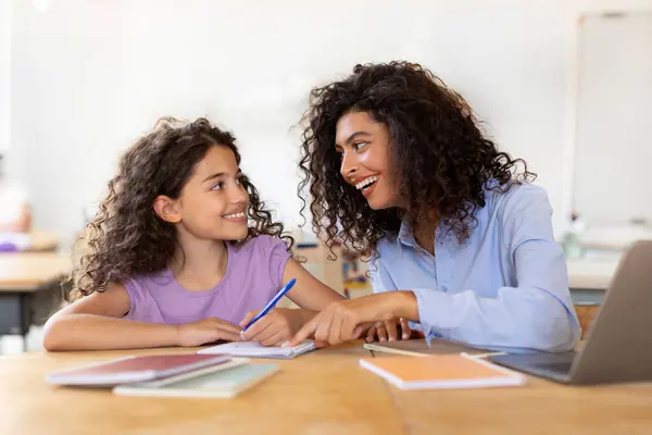 Mother helping daughter to do lessons, tutor is engaged with child, teaching to write and count, school lessons with teacher