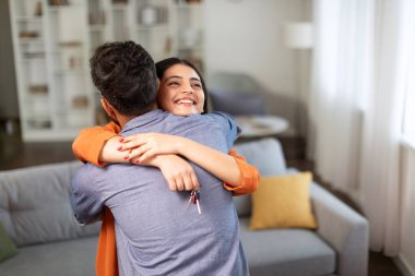 Yeni evim. Mutlu Hintli eş ev anahtarlarını tutuyor ve kocaya sarılıyor, birlikte yeni bir eve taşınıp taşınmayı kutluyorlar.