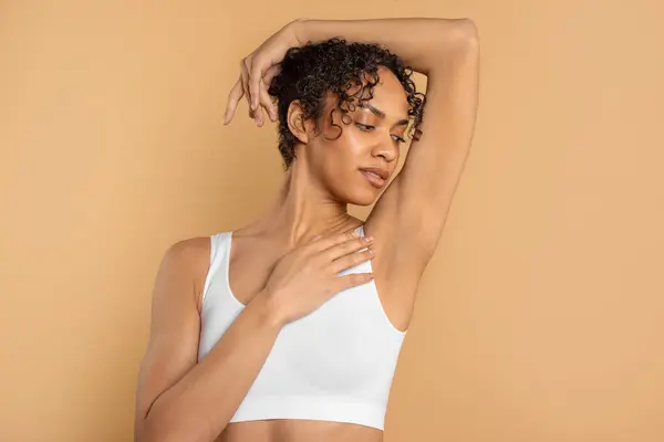 stock image Young latin woman with perfect soft armpit skin enjoying results of routine procedures, ad for under arm deodorant and epilation, beige background