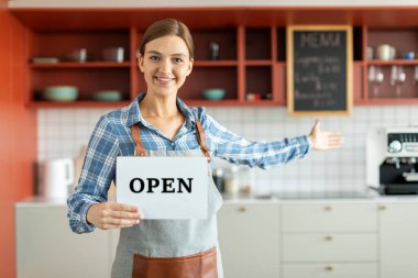 Bayan kahve dükkânı sahibinin portresi sizi içeri davet ediyor ve açık tabela tutuyor, gülümseyen bayan içeride duruyor, boş yer var.