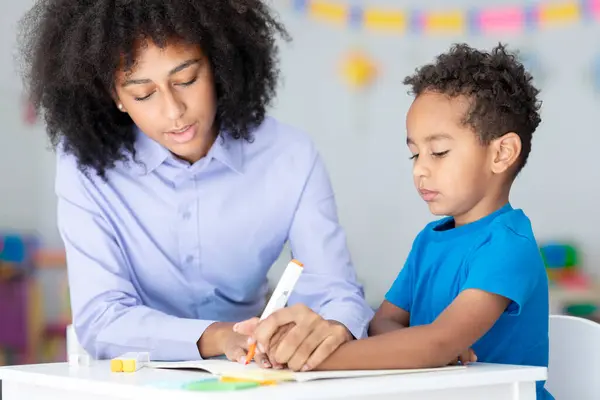Kleiner Intelligenter Schwarzer Junge Lernt Mit Einer Lehrerin Und Schreibt — Stockfoto