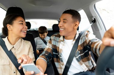 Pozitif aile araba kullanıyor, akıllı telefon kullanıyor ve harita navigasyonunu kontrol ediyor, anne ekranı gösteriyor, baba araba kullanıyor, çocuk arka koltukta oturuyor.