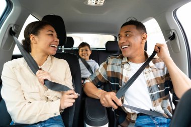 Üç kişilik neşeli bir aile yeni bir arabaya biniyor, kadın ve erkek emniyet kemeri takıyor. Ulaşım, yeni otomobil konsepti