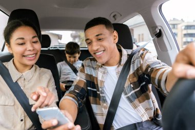 Kısa yol güzergahı. Aile arabanın içinde oturuyor ve akıllı telefon kullanıyor. Erkek sürücü telefonu tutuyor, yeri gösteriyor.