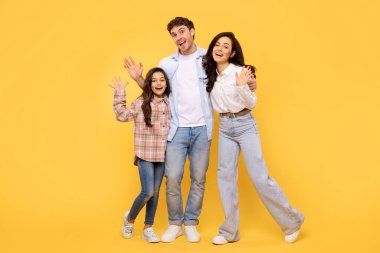 Hoş geldiniz. Üç el sallayan ve gülümseyen, sarı arka planda duran heyecanlı Avrupalı aile. Anne, baba ve kız selamlarını iletiyorlar.