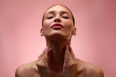 Elbiseleri olmayan, boynu kapalı, boynu kapalı, pastel pembe arka planda izole bir şekilde poz veren, arka planda duran...