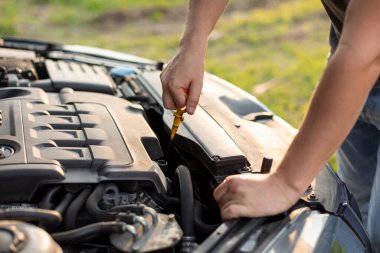 İnsan el ele tutuşup motorun yağ seviyesini kontrol eder. Yolculuk öncesi veya araba ile, yakın plan. Araba kontrolü konsepti