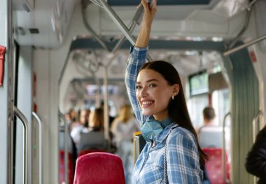 Modern tramvayda ayakta duran mutlu yolcu bayan kapalı alanlarda, otobüslerle veya tramvaylarla rahat bir yolculuk yapıyor.