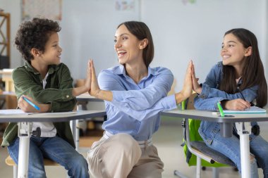 Mutlu Avrupalı bayan öğretmen, liseli kız ve okul çocuğu tezahürat yapıyor, beşlik çakıyor ve gülümsüyor, testlerden tatmin oluyor.