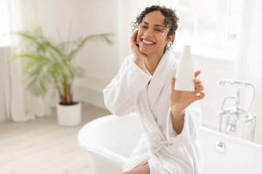 En sevdiğim kozmetik ürünüm. Banyo yaptıktan sonra şişeyi elinde tutan ve neşe ifade eden kadın, şampuan ya da duş jeli tavsiye eder