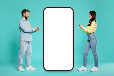 Pozitif Avrupalı erkek ve kadın beyaz ekranlı büyük akıllı telefona doğru yürüyorlar ve cep telefonlarını kullanıyorlar.