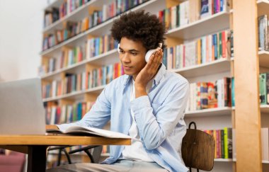 Zeki Afrikalı Amerikalı öğrenci üniversite sınavı için internetten öğreniyor, dizüstü bilgisayar kullanıyor ve kulaklık takıyor.