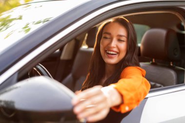 Araba test sürüşü sırasında yan aynaya dokunup bakan heyecanlı kadın, yeni bir otomobil almadan önce