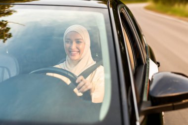 Lüks bir arabada oturup sabah işe giderken tesettürlü mutlu Müslüman iş kadını.