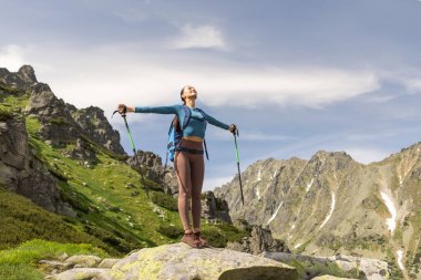 Elleri açık duran sırt çantalı genç bir kadın sihirli dağ manzarasına hayran.