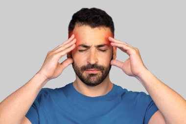 Baş ağrısı olan orta yaşlı bir adam şakaklarına dokunuyor gri stüdyo arka planında duygusal bir fotoğraf, boş bir alan. Üzgün bir adam kırmızı alnıyla hafifçe ovuyor, migreni var. Yüksek kalite fotoğraf
