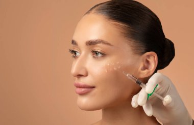 Cosmetologist making rejuvenating anti wrinkle injections on young woman face. Female aesthetic cosmetology in a beauty salon. Free space clipart