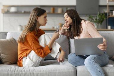 Anne kanepede oturuyor, dizüstü bilgisayarla genç kızı gözetliyor cep telefonu kullanıyor, anne ve çocuk boş vakitlerini cihazlarla birlikte geçiriyorlar. Ebeveyn kontrolü ve akıllı telefon nesli