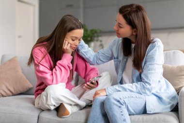 Destekleyici anne üzgün ergen kızını teselli ediyor arkadaşları tarafından reddediliyor, anne depresyondaki kıza sorunlarıyla başa çıkması için yardım ediyor, çocuk cep telefonuna bakıyor.