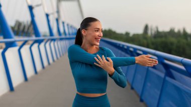 Motivasyon konsepti. Spor antrenmanı yapan mutlu sporcu kadın koşmadan önce ellerini ve vücudunu esnetiyor.