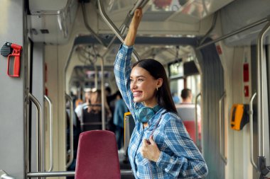 Toplu taşıma aracında duran kadın yolcu, modern tramvayda veya otobüste gezintiden zevk alan güzel bir kadın.